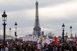 a huge group of protesters march in front of the EIffel tower