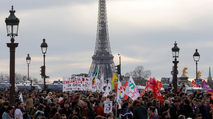 a huge group of protesters march in front of the EIffel tower