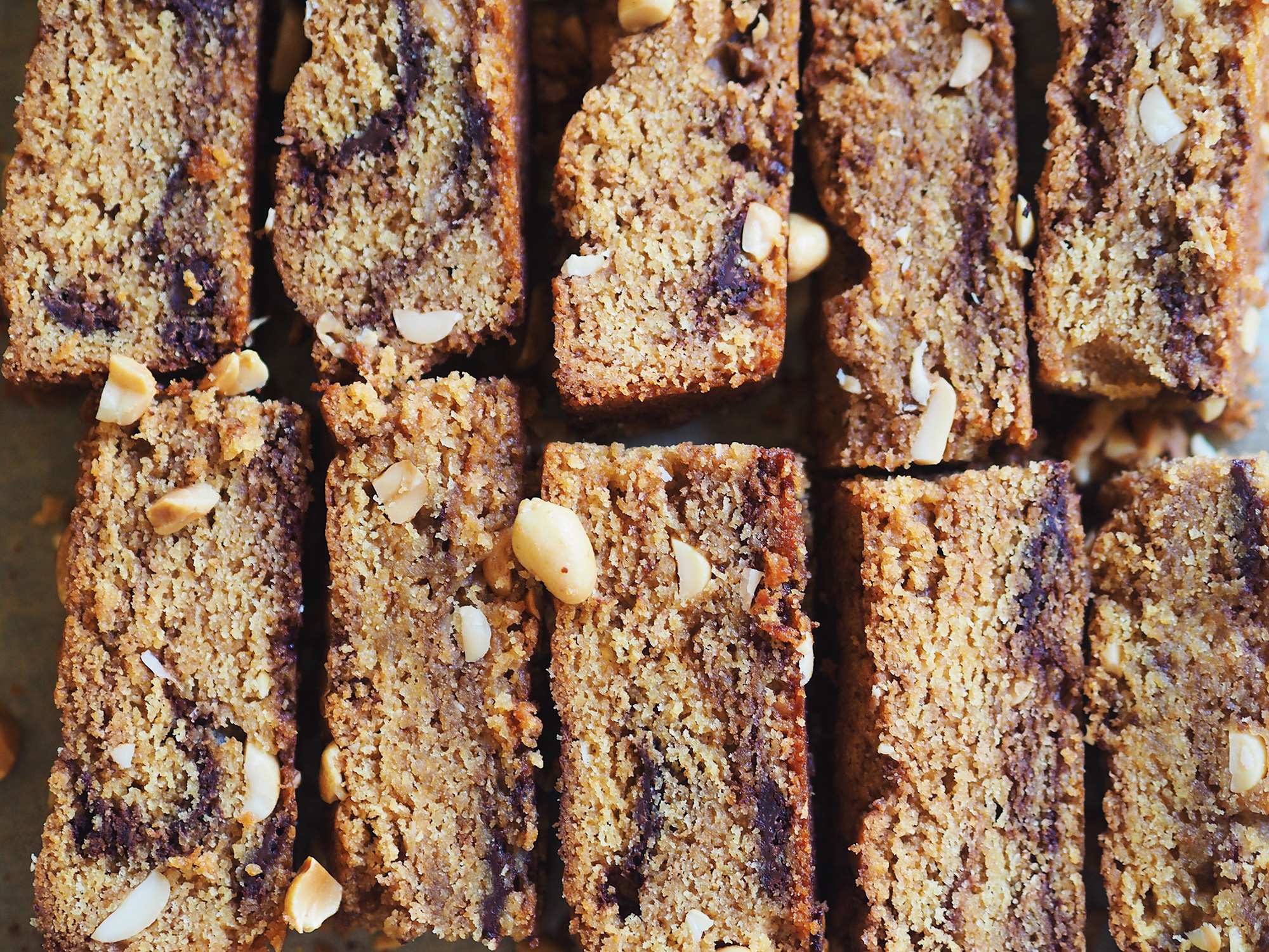 A close up of freshly baked peanut butter and chocolate blondies lined up on a baking sheet, an easy baking project.