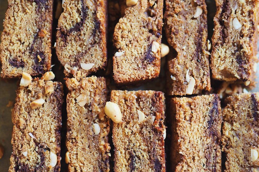 A close up of freshly baked peanut butter and chocolate blondies lined up on a baking sheet, an easy baking project.