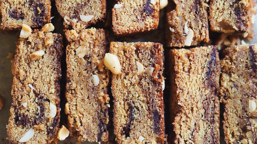 A close up of freshly baked peanut butter and chocolate blondies lined up on a baking sheet, an easy baking project.