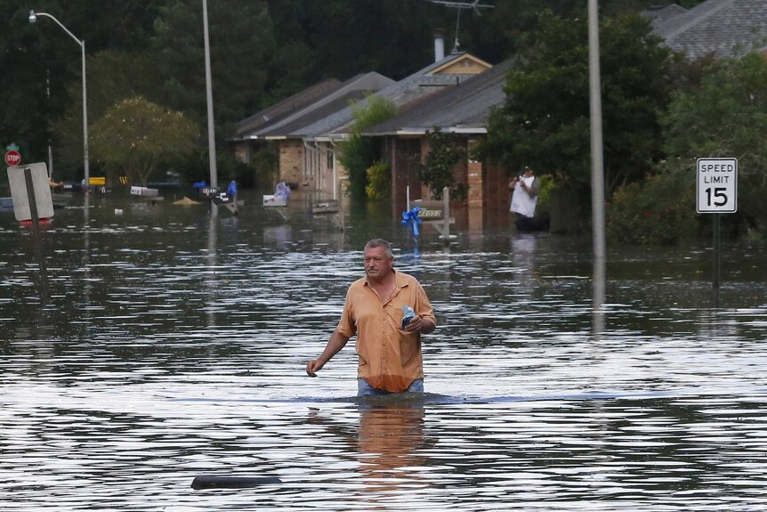 A man wades through a flooded street.