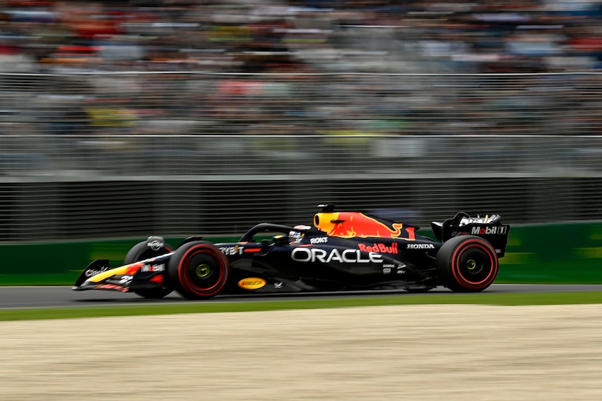 Max Verstappen in his Red BUll F1 car driving on track at Albert Park in Melbourne past a grandstand