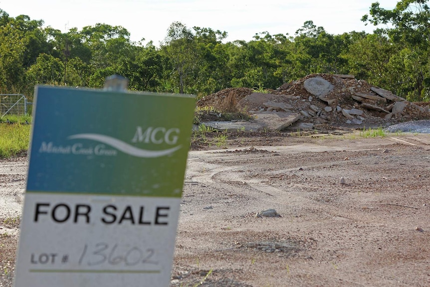 A photo of a vacant lot of land in Mitchell Creek Green, with debris visible in the background.