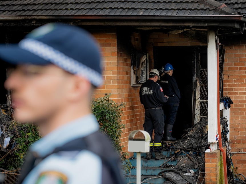 Police and fire inspectors outside a burnt-out home.
