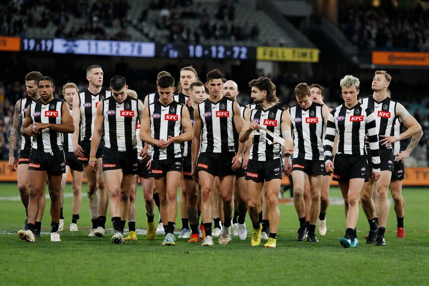 Collingwood players look disappointed as they walk off the field
