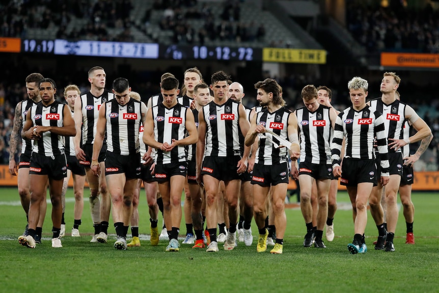 Collingwood players look disappointed as they walk off the field