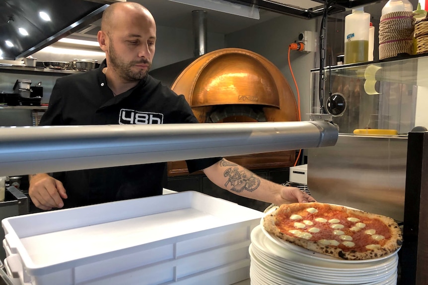 Michele Circhillo puts a pizza out at the pass in a restaurant