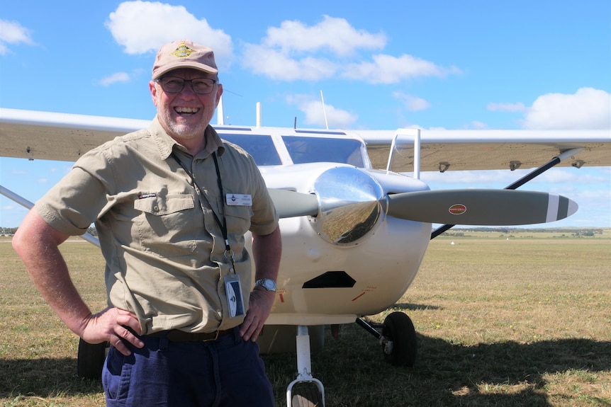 A man standing in front of an aeroplane with a big smile on his face.