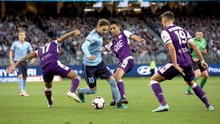 Three Perth defenders surround Milos Ninkovic, who maintains control of the ball.