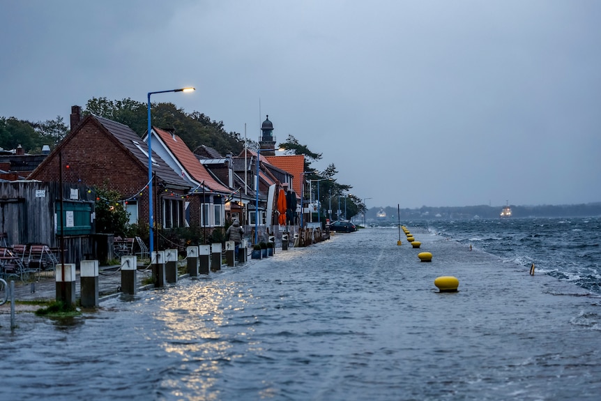 A flooded street next to the sea in a European town at dusk