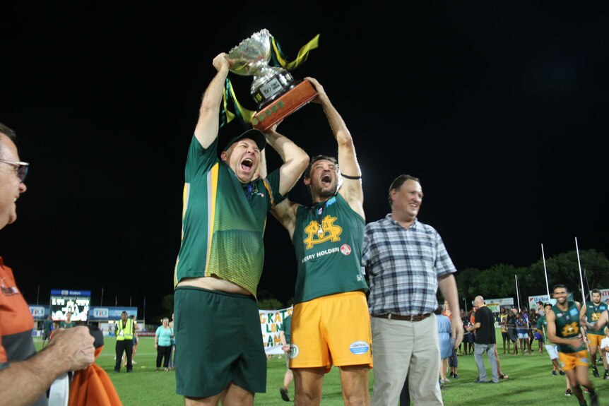 St Marys coach Rick Nolan and Captain Peter MacFarlane celebrate the team's grand final win by lifting the cup over their heads.