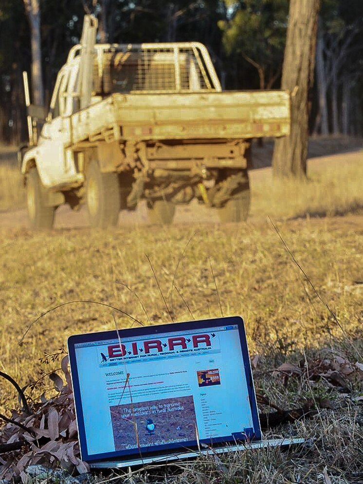 A laptop sits on the ground, with the BIRRR webpage displayed; a tray-back utility is in the background