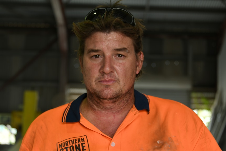 A disgruntled builder stands in a warehouse.