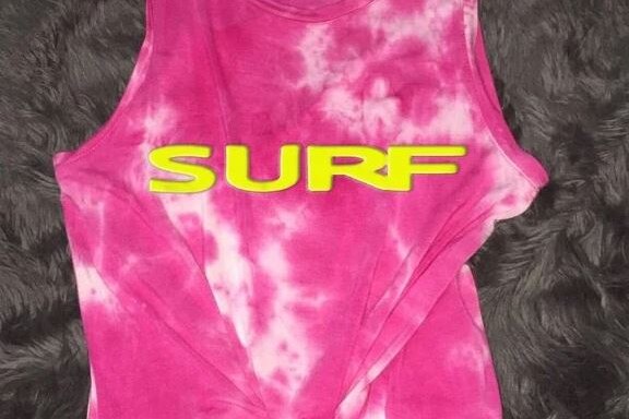 Pink tie-dyed tank top with yellow letters that spell SURF.