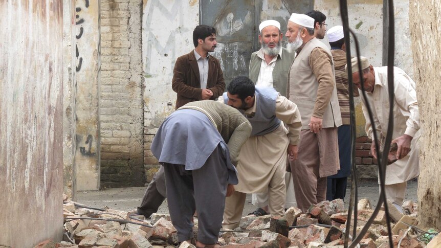 Residents in Pakistan gather to clear a path after it was damaged by an earthquake