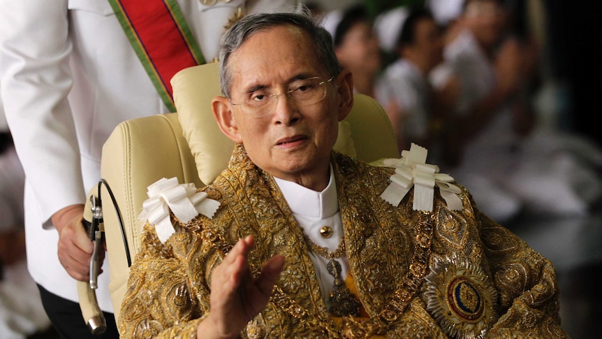 Thailand's King Bhumibol Adulyadej wearing an extravagent gold jacket, waving as he returns to hospital.