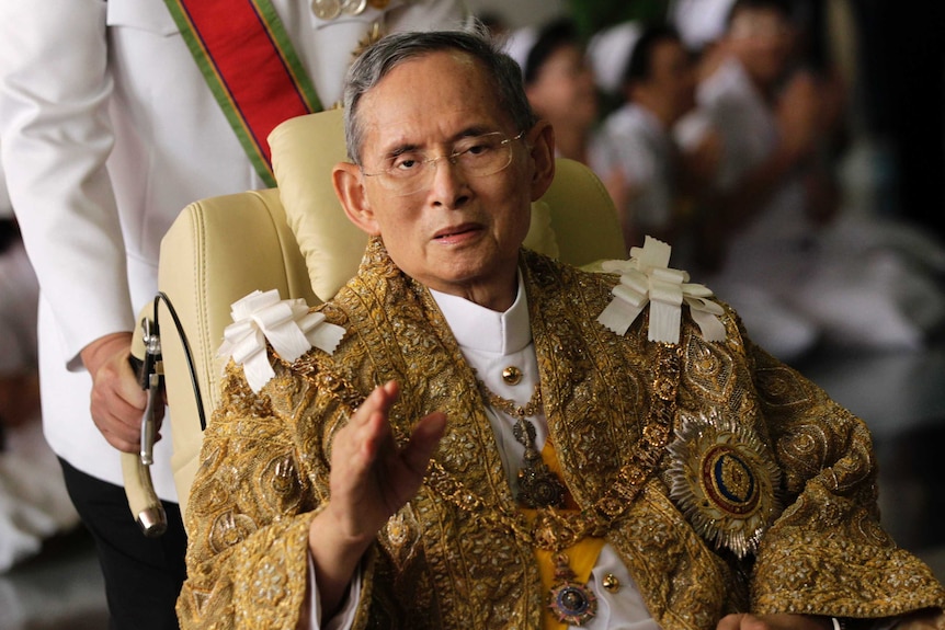 Thailand's King Bhumibol Adulyadej wearing an extravagant gold jacket, waving as he returns to hospital.