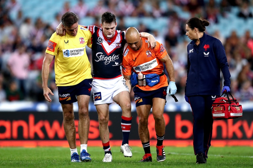 A Sydney Roosters NRL player is helped from the field after sustaining a knee injury.