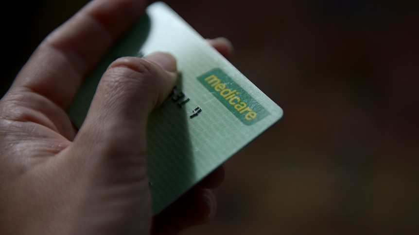 A hand holds a medicare card