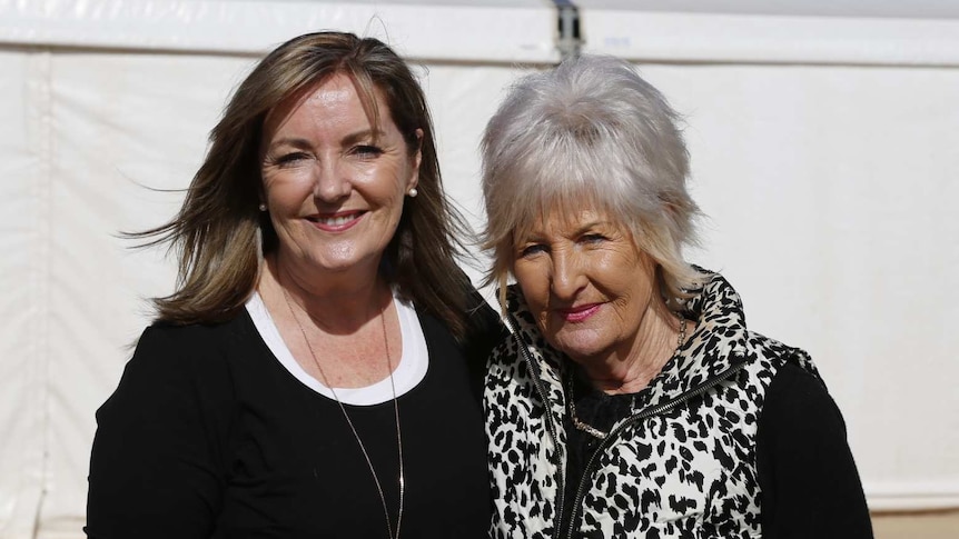 Two women are outdoors in a portrait with a white gazebo behind them.