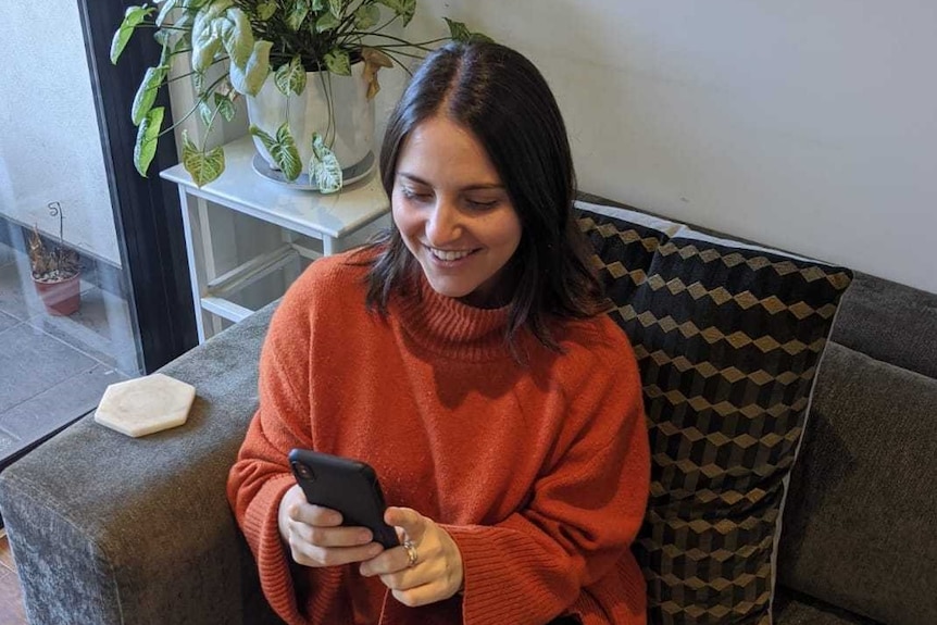 A young woman leaning on a couch and staring into her phone
