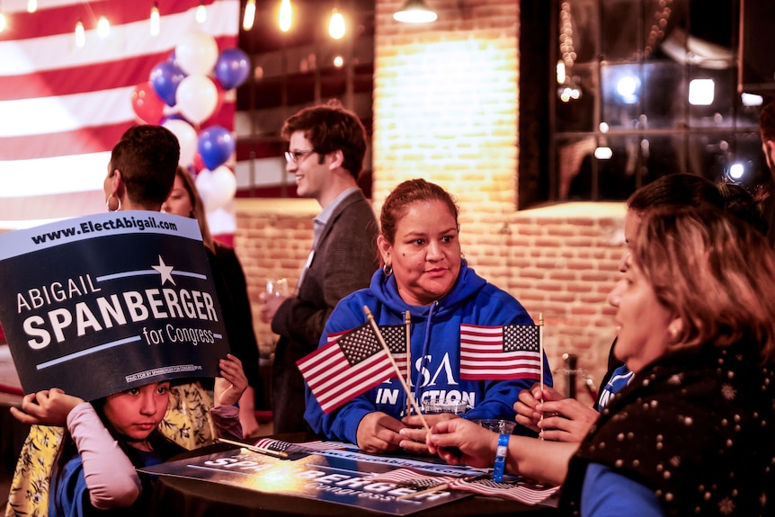 Two women and a child sit at a table with little American flags on it 