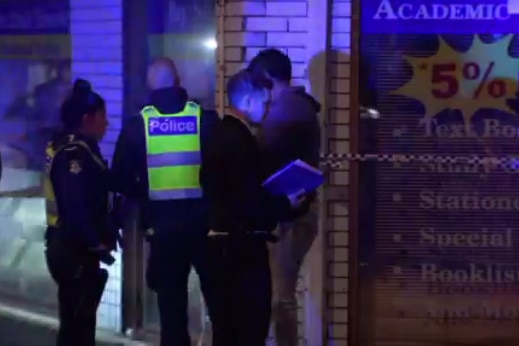 Police officers are illuminated by blue light at a crime scene in the dark.