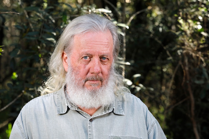 Older man with white hair and beard wearing a grey t-shirt