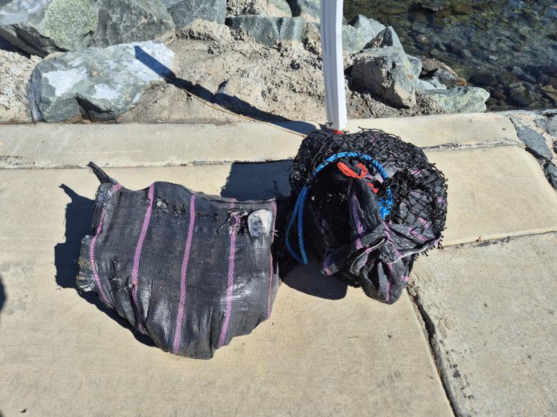 Two large black packages resting on a cement boat ramp.