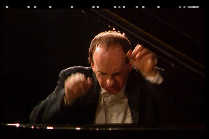 Roger Woodward his hands blurring above the piano keyboard, his head down.