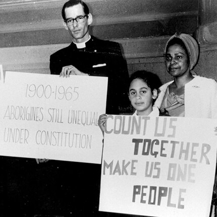Four people stand holding signs, one of which reads 'count us together, make us one people'.
