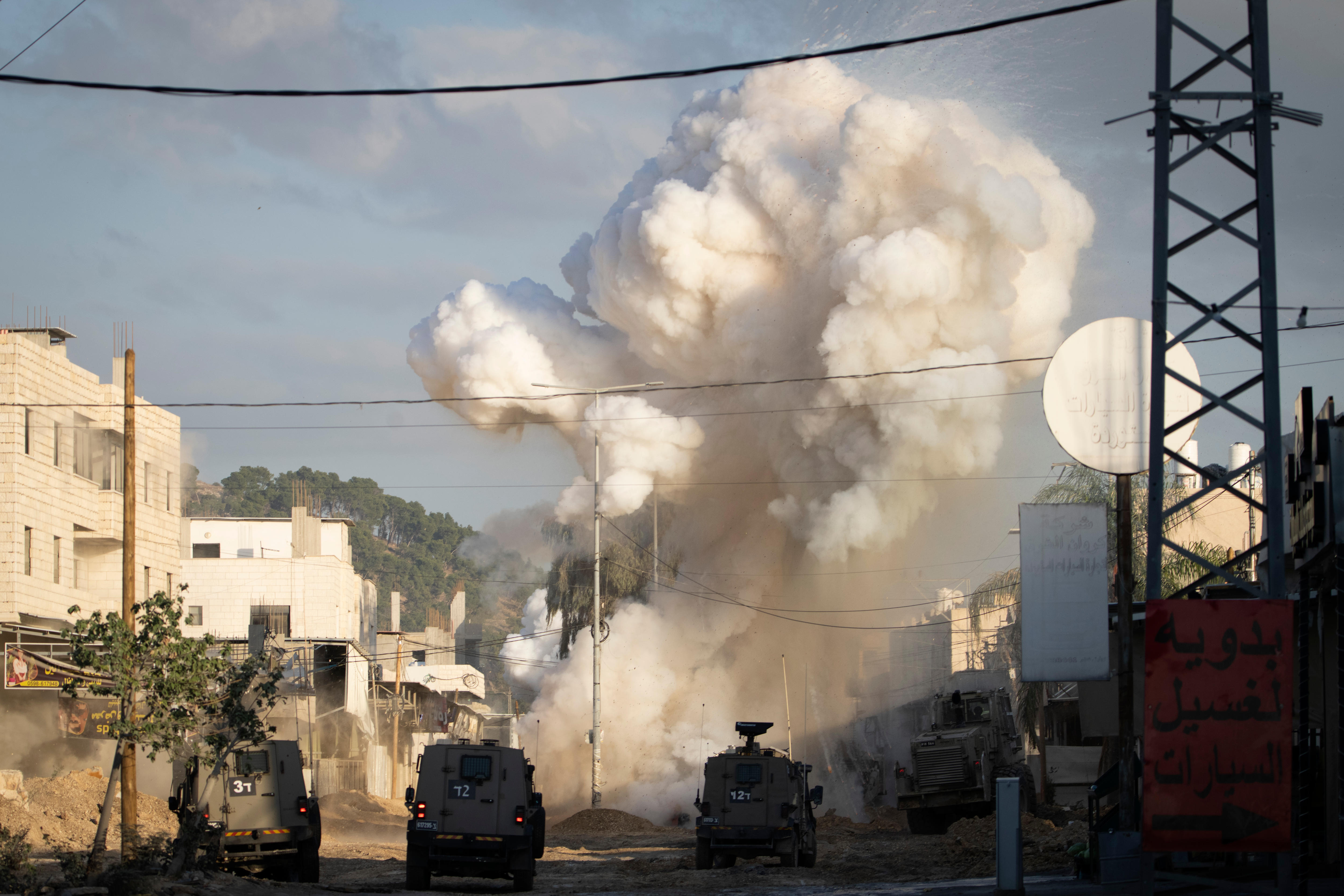 A cloud of smoke billowing up behind two armoured vehicles