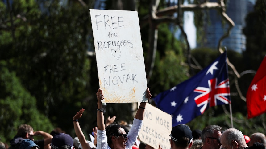 A protestor holds a placard calling for both the refugees and Novak Djokovic to be freed, January 8, 2022.