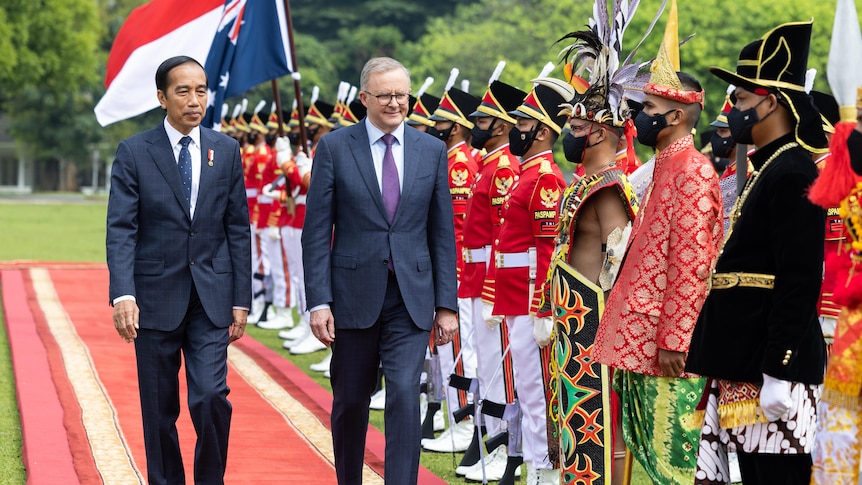 Two men walk by a ceremonial guard