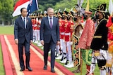 Two men walk by a ceremonial guard