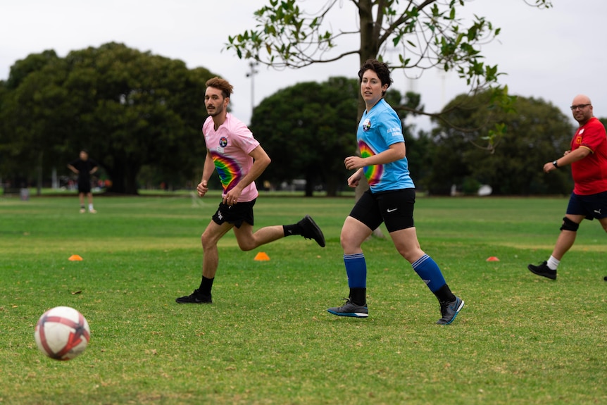 Two people from opposing teams run towards the football during a game.