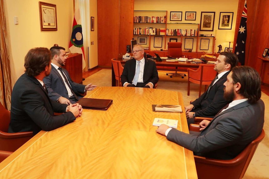 Five men including the Prime Minister at the head of a table gather around and discuss