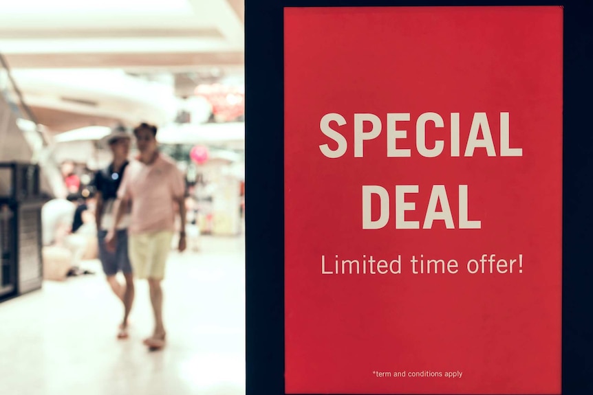 Two men walk past a special deal sign