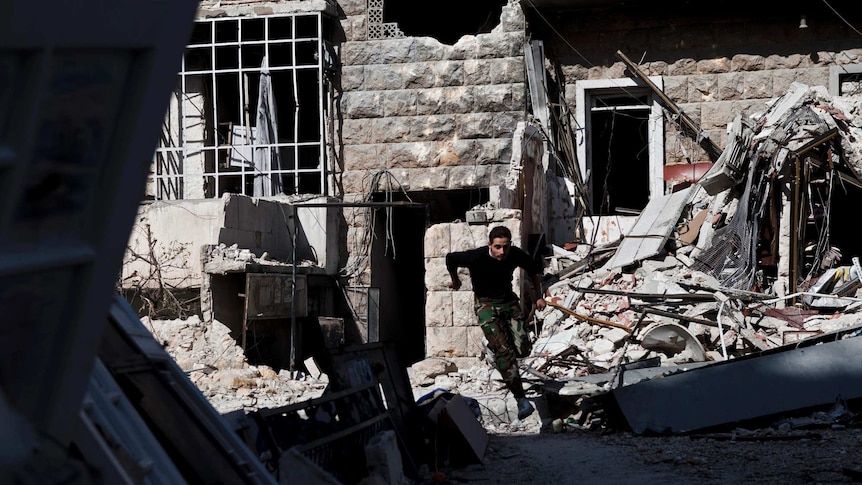 A fighter from the Free Syrian Army leaps across debris