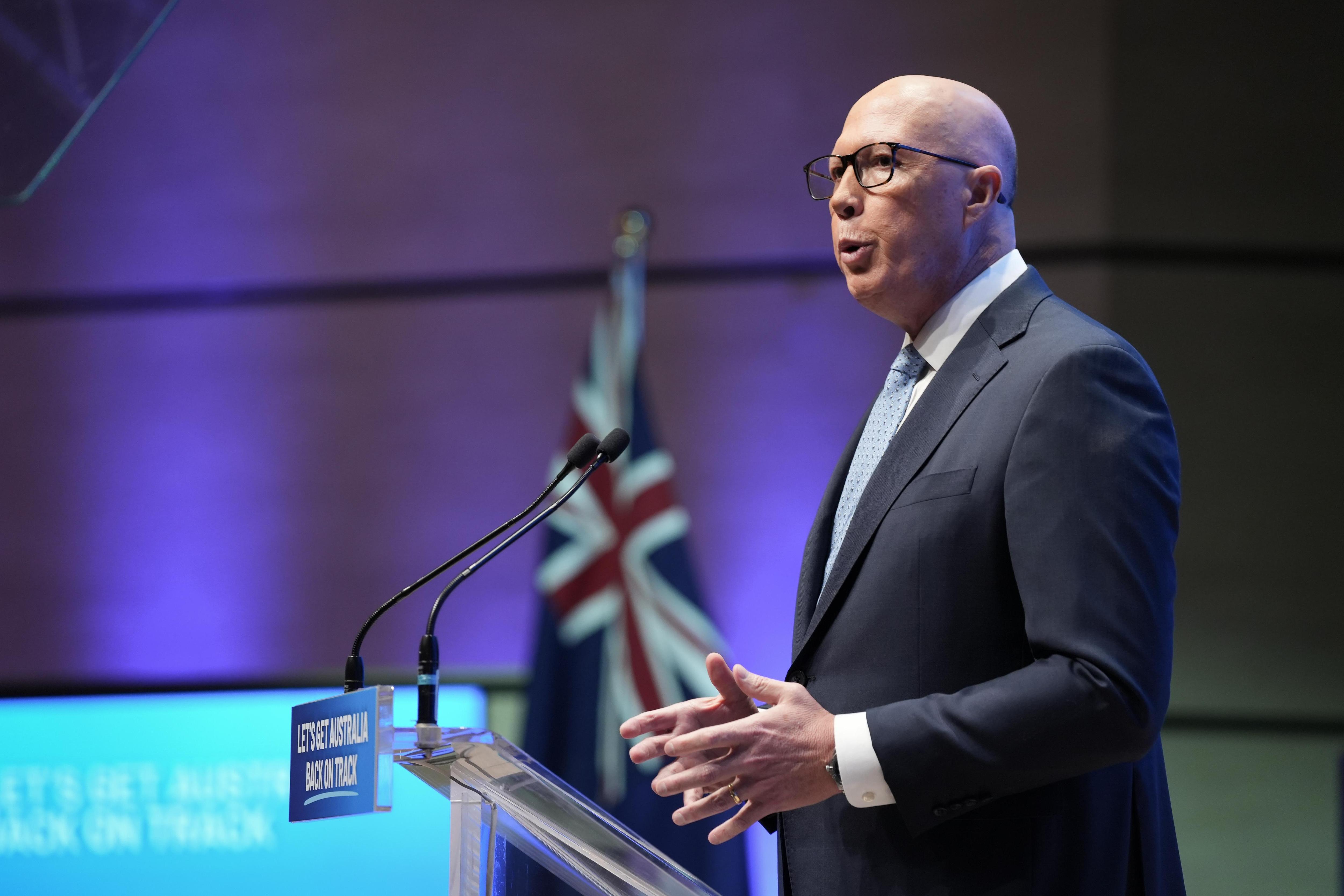 一位男性政治家在讲台上发表演讲，背景是一面澳大利亚国旗