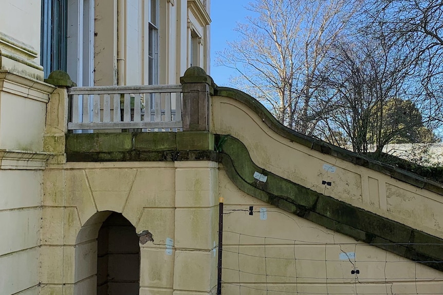 An old staircase is cracked and has green mould growing on it