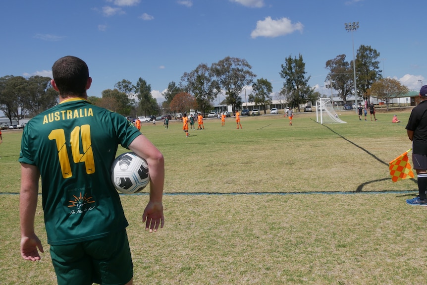 A young man in an green Australia jersey prepares to throw in the ball from the touchline of the pitch.