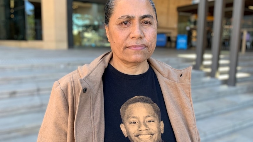 A woman with a photo of her dead teenage son on her T-shirt