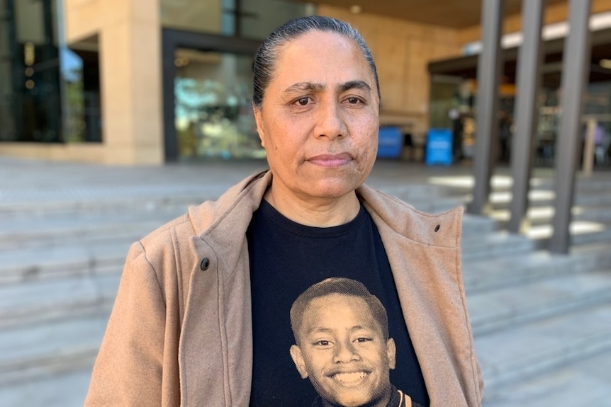 A woman with a photo of her dead teenage son on her T-shirt