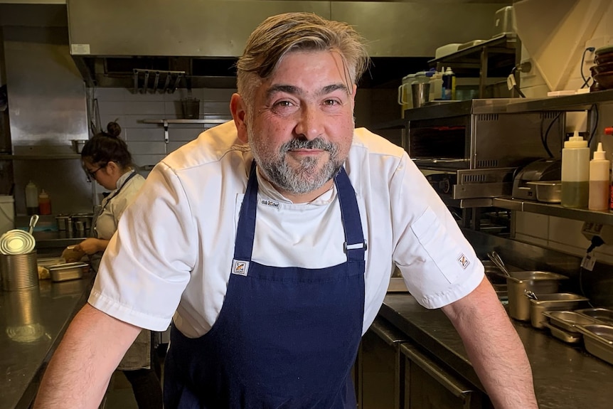 A man wearing a navy blue chef's apron.