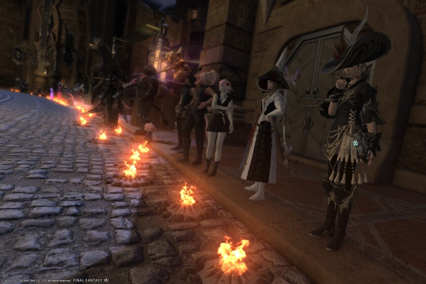 A number of virtual avatars stand in a row, with campfire animations in front of each of them.