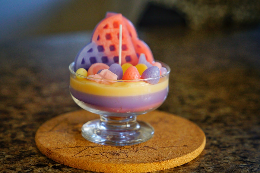 A candle that looks like a dessert, in a glass.