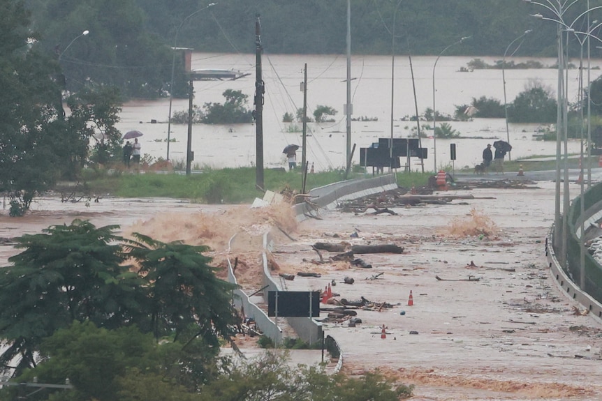 Water flooding a road and flowing over a bridge. 