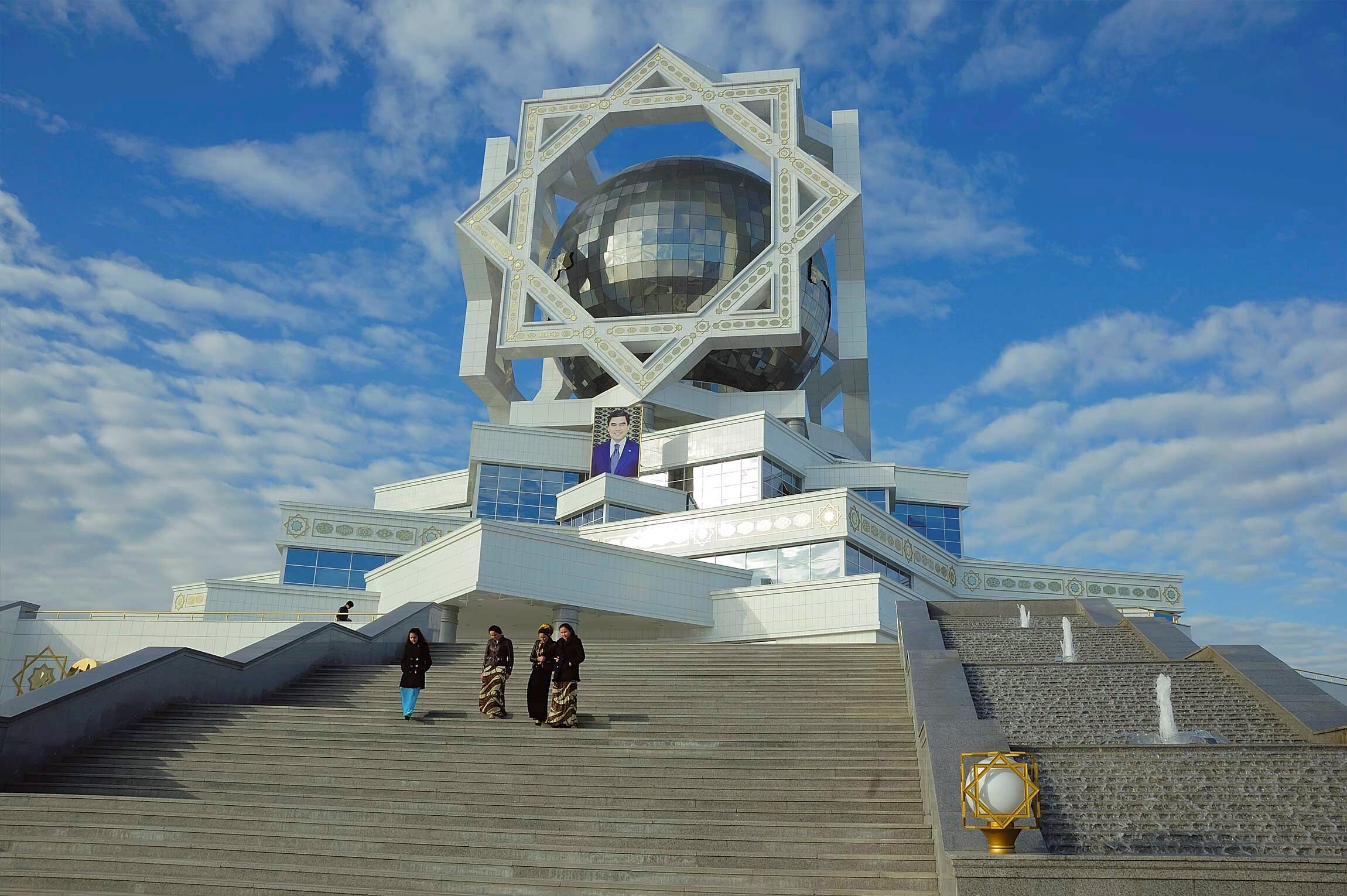 Women walk down steps beneath a portrait of Turkmenistan's President Gurbanguly Berdimuhamedow.